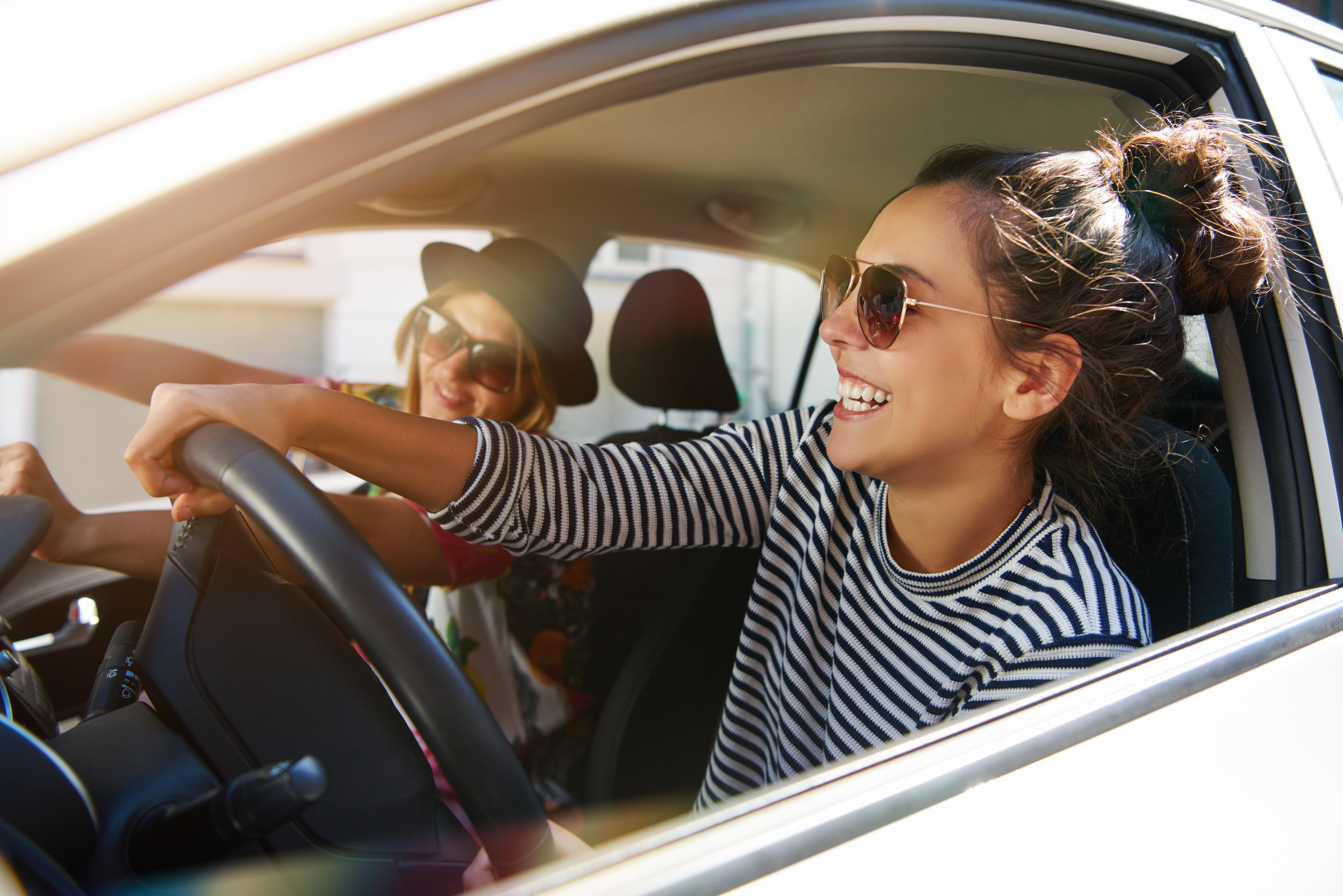 friends driving in the car during sunset laughing and smiling